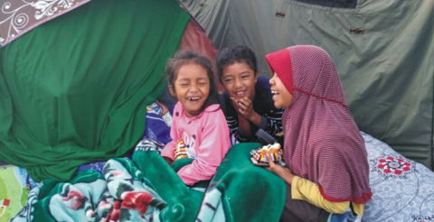 Foto tiga anak kecil yang sedang tertawa